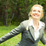 Portrait of happy businesswoman in suit in a natural environment